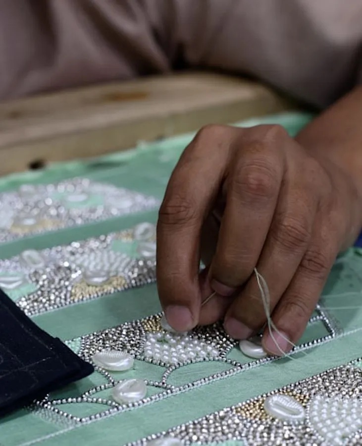 Hands of an artisan embroidering fabric